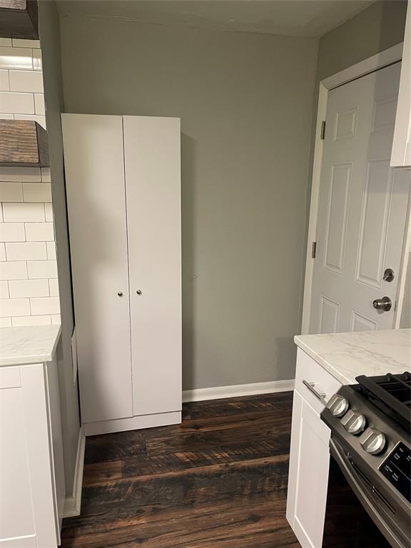 kitchen featuring white cabinets, dark hardwood / wood-style flooring, black stove, and tasteful backsplash