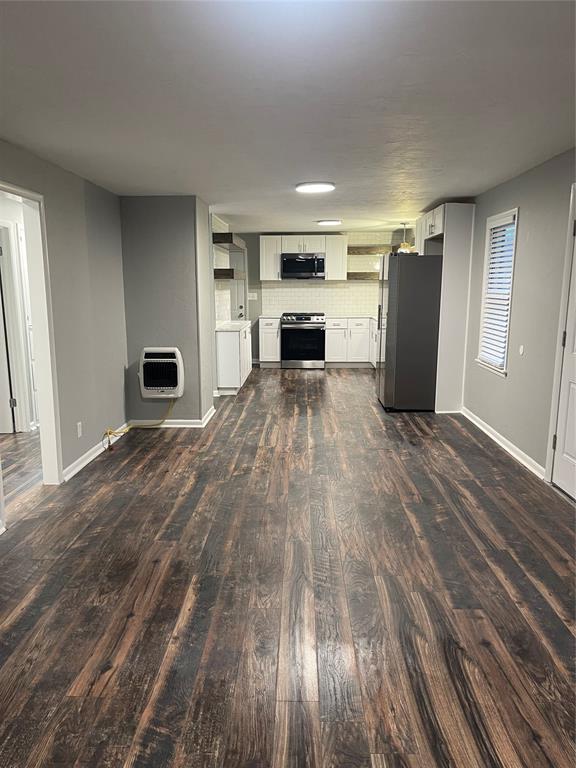 unfurnished living room featuring dark hardwood / wood-style flooring and heating unit