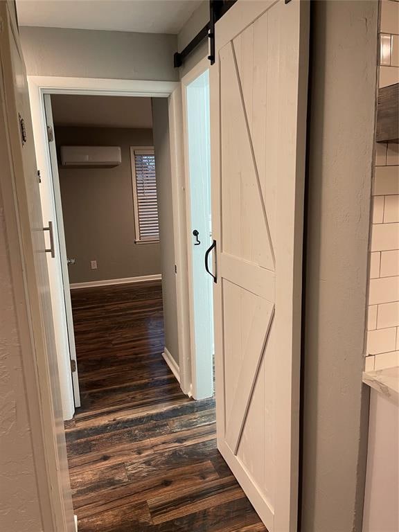 hallway featuring a wall mounted air conditioner, dark hardwood / wood-style floors, and a barn door