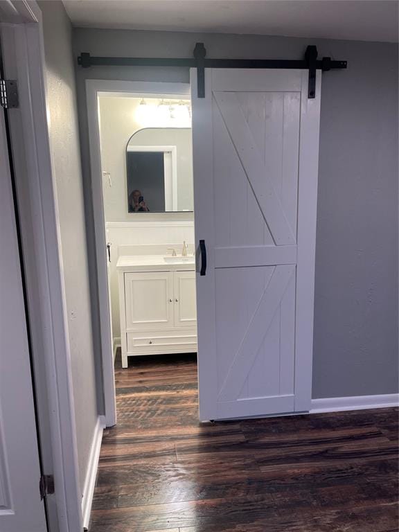 hallway with a barn door and dark hardwood / wood-style floors