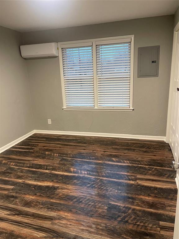 empty room featuring dark hardwood / wood-style flooring, electric panel, and a wall unit AC