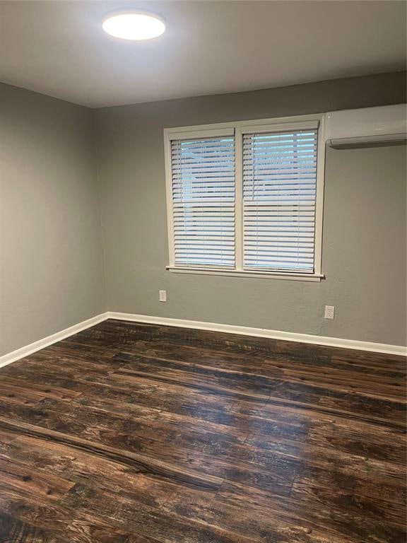 spare room with dark wood-type flooring and a wall unit AC