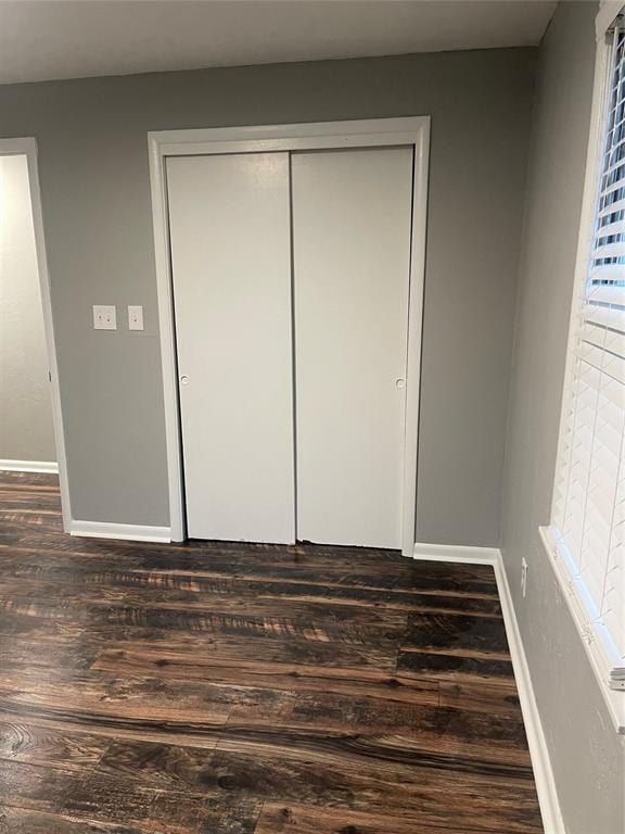 unfurnished bedroom featuring dark hardwood / wood-style floors and a closet