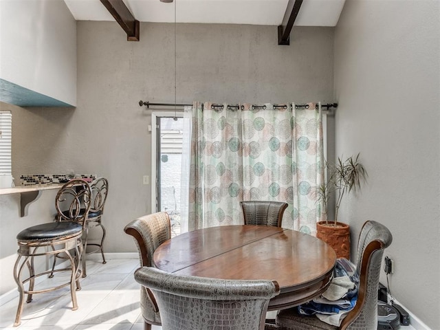 tiled dining space featuring beam ceiling