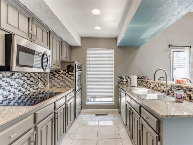 kitchen with gray cabinets, sink, stainless steel appliances, and tasteful backsplash