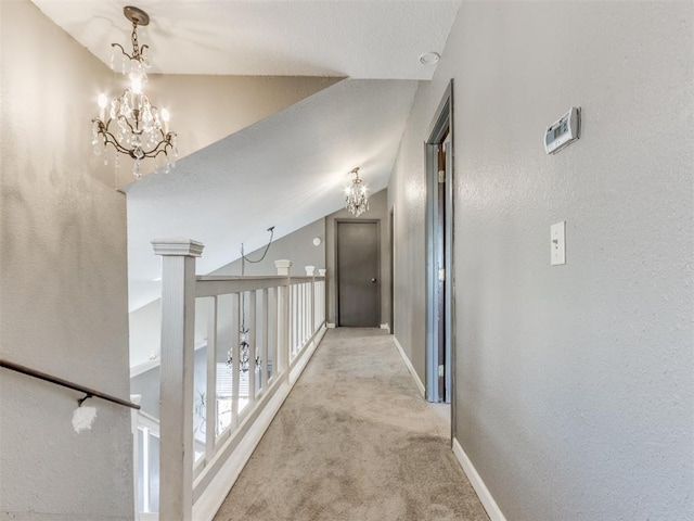 hallway featuring lofted ceiling, light carpet, and a chandelier