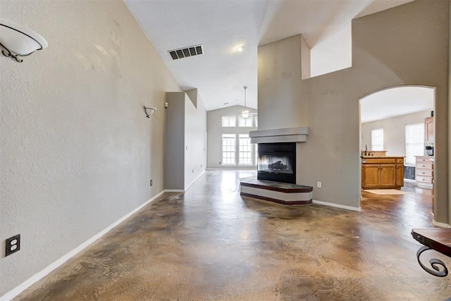 unfurnished living room featuring a multi sided fireplace and high vaulted ceiling