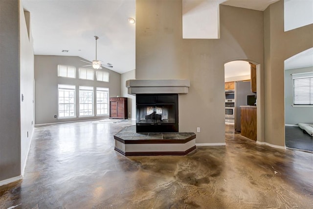 living room featuring ceiling fan, a healthy amount of sunlight, concrete floors, and high vaulted ceiling