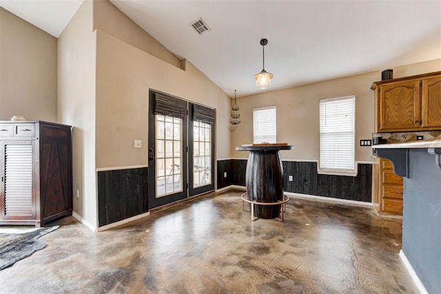 kitchen with pendant lighting, a healthy amount of sunlight, vaulted ceiling, and wood walls