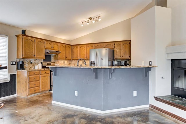 kitchen featuring concrete flooring, a breakfast bar, lofted ceiling, kitchen peninsula, and stainless steel appliances