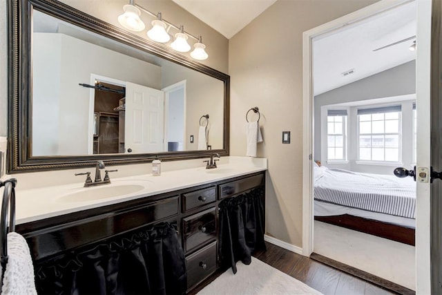 bathroom with hardwood / wood-style flooring, vanity, and vaulted ceiling