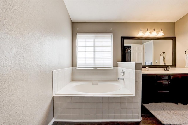 bathroom featuring vanity and tiled bath