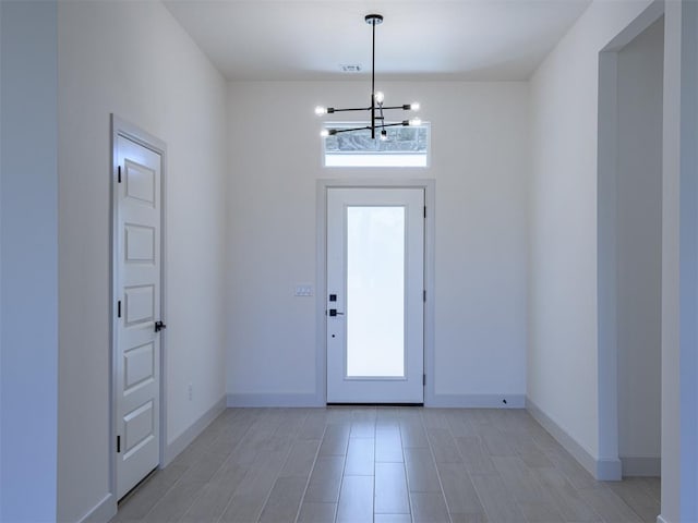 foyer entrance with light hardwood / wood-style flooring and a notable chandelier