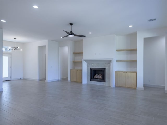 unfurnished living room featuring wood-type flooring and ceiling fan with notable chandelier