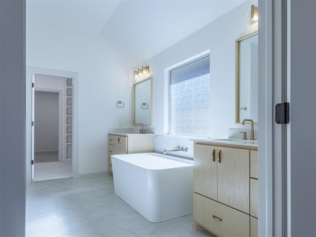 bathroom featuring a bathing tub, tile patterned flooring, vanity, and vaulted ceiling