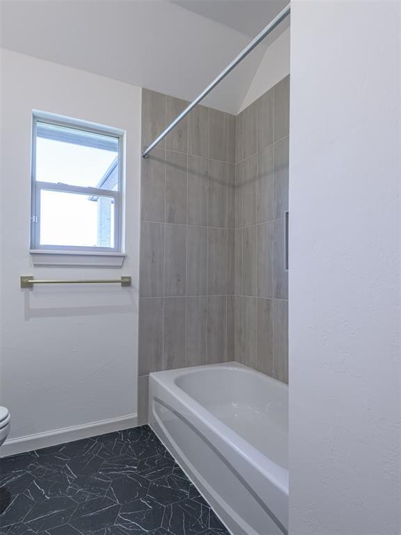 bathroom with tiled shower / bath combo and toilet