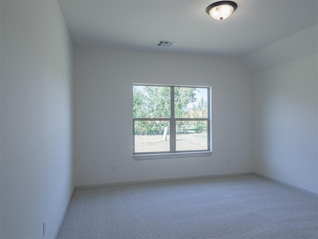 spare room featuring light carpet and vaulted ceiling