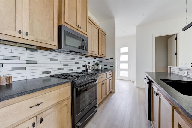 kitchen with light brown cabinetry, light wood-type flooring, tasteful backsplash, black range with gas cooktop, and dishwasher