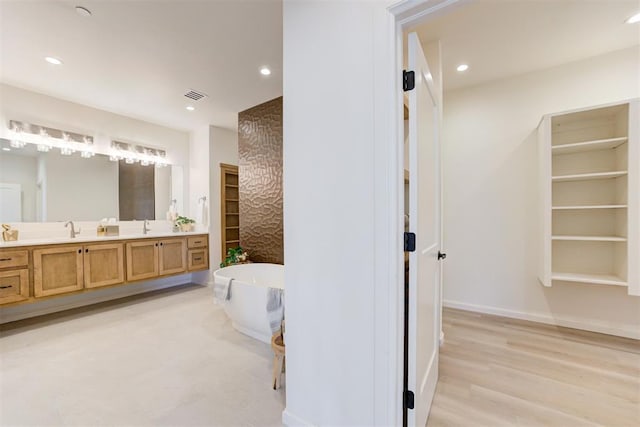 bathroom with hardwood / wood-style floors, vanity, and a tub to relax in