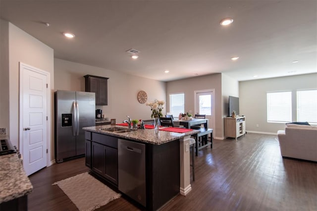 kitchen with dark brown cabinetry, stainless steel appliances, sink, dark hardwood / wood-style floors, and an island with sink