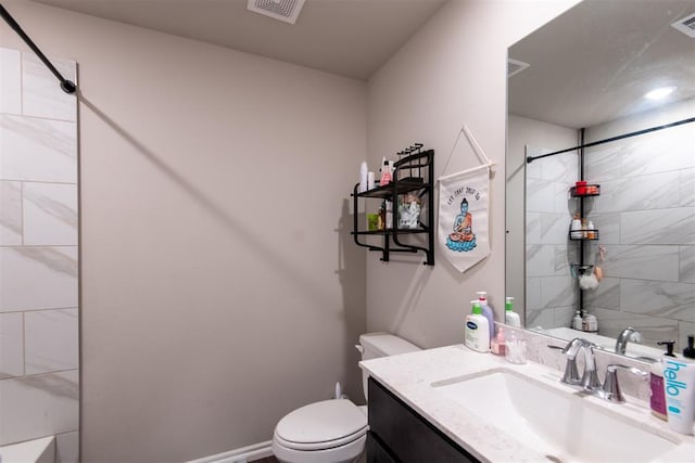 bathroom featuring vanity, toilet, and tiled shower