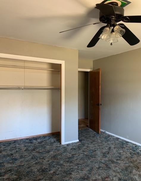 unfurnished bedroom featuring dark colored carpet, ceiling fan, and a closet