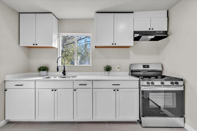 kitchen with gas stove, white cabinetry, sink, and light tile patterned flooring