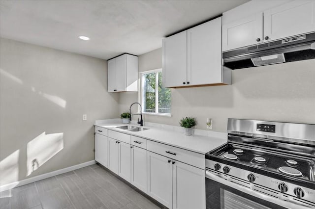 kitchen featuring white cabinets, stainless steel gas range oven, and sink