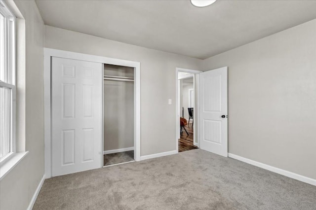 unfurnished bedroom featuring carpet flooring, a closet, and multiple windows