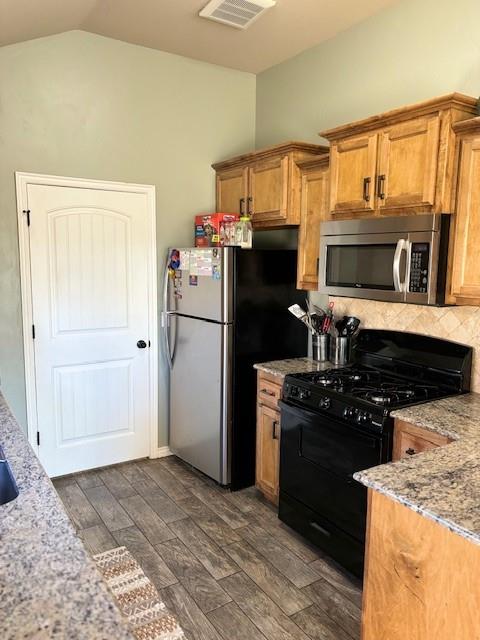 kitchen with light stone countertops, appliances with stainless steel finishes, and dark hardwood / wood-style floors