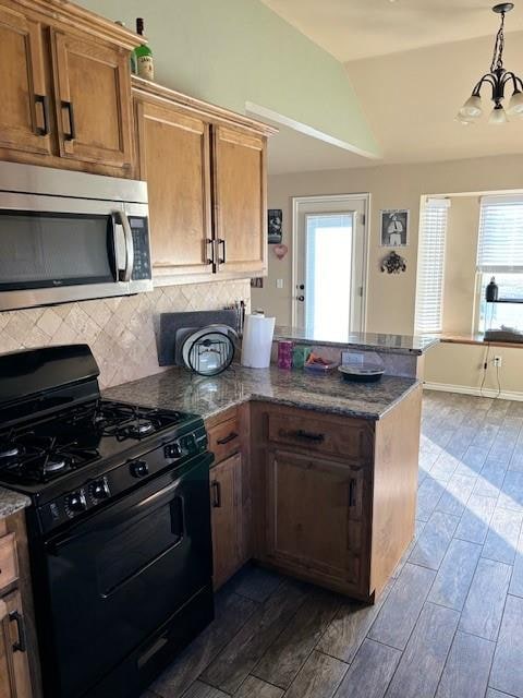 kitchen with plenty of natural light, black range with gas stovetop, a chandelier, and vaulted ceiling