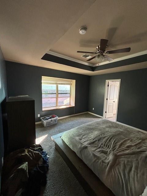 carpeted bedroom with ceiling fan, crown molding, and a tray ceiling