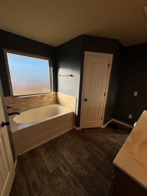 bathroom with a washtub, wood-type flooring, and vanity