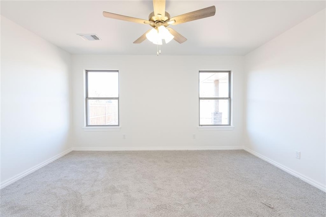 empty room featuring plenty of natural light, baseboards, visible vents, and ceiling fan