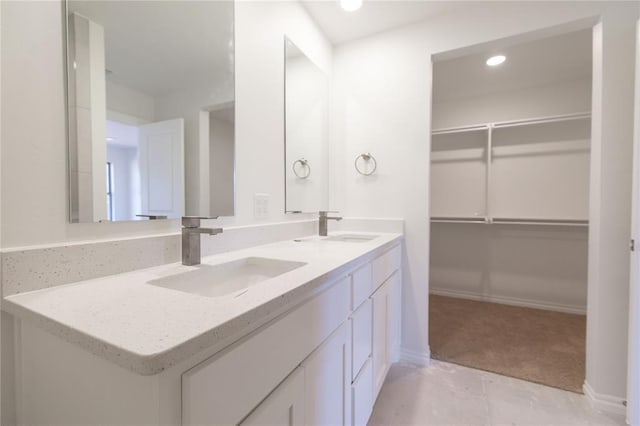 full bathroom featuring a walk in closet, double vanity, recessed lighting, and a sink