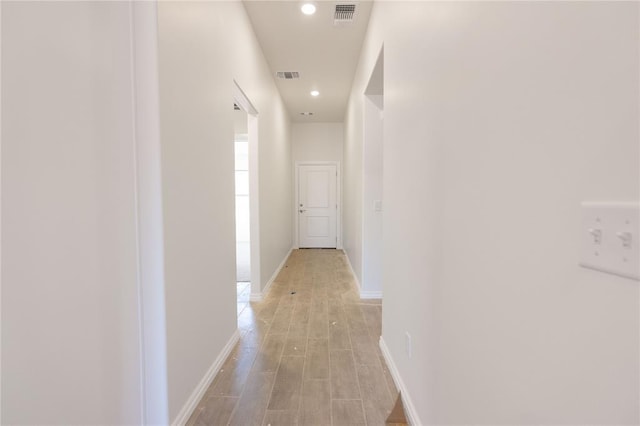 hallway featuring light wood-type flooring, visible vents, baseboards, and recessed lighting