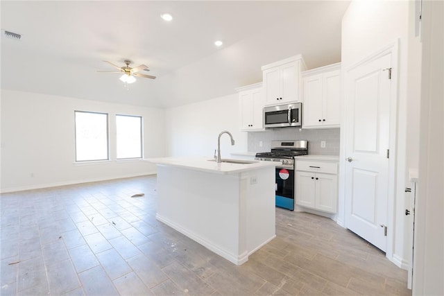 kitchen with visible vents, a kitchen island with sink, a sink, appliances with stainless steel finishes, and tasteful backsplash