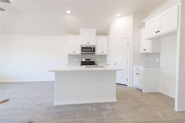 kitchen featuring an island with sink, a sink, white cabinetry, stainless steel appliances, and light countertops