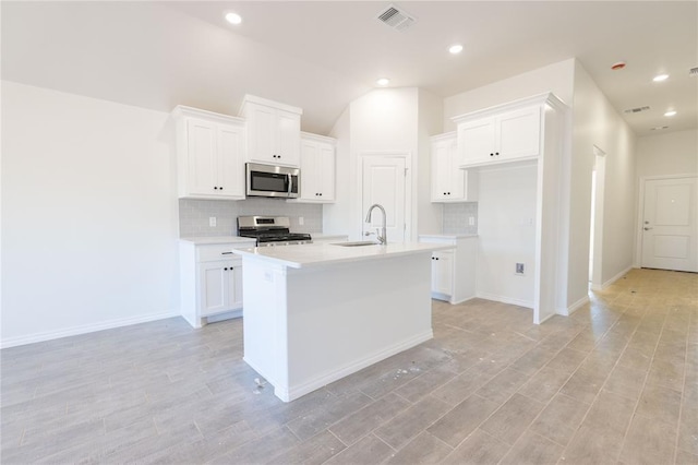 kitchen featuring visible vents, light countertops, white cabinets, stainless steel appliances, and a sink