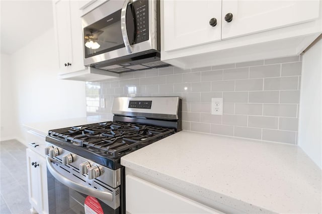 kitchen featuring tasteful backsplash, white cabinets, stainless steel appliances, and light stone counters