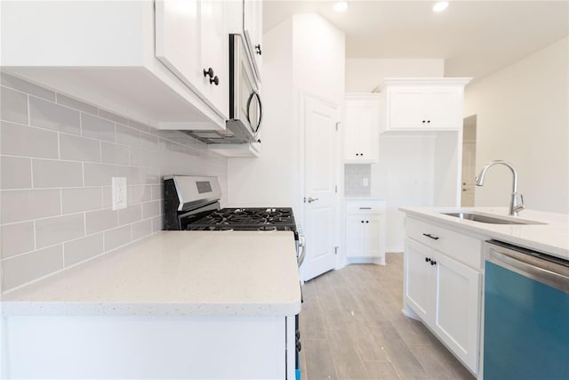 kitchen with a sink, decorative backsplash, appliances with stainless steel finishes, and white cabinets