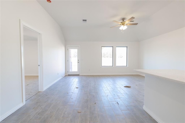 unfurnished room with visible vents, baseboards, vaulted ceiling, light wood-style floors, and a ceiling fan