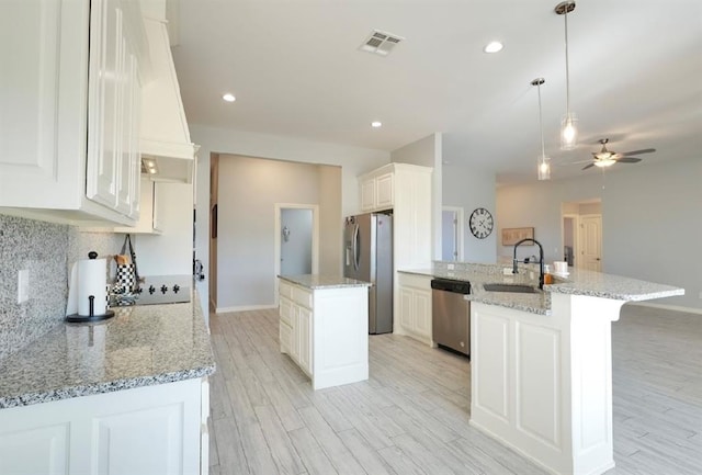 kitchen with pendant lighting, an island with sink, stainless steel appliances, and sink