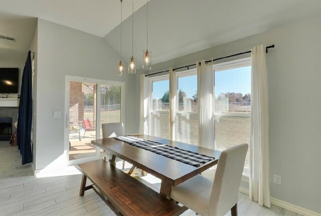 dining area featuring lofted ceiling, light hardwood / wood-style flooring, and a healthy amount of sunlight