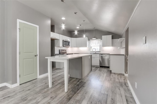 kitchen featuring a center island, lofted ceiling, white cabinets, decorative light fixtures, and stainless steel appliances