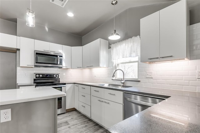 kitchen featuring white cabinets, pendant lighting, light hardwood / wood-style floors, and stainless steel appliances