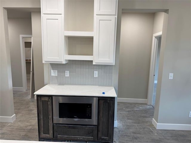 kitchen featuring backsplash, white cabinetry, and built in microwave