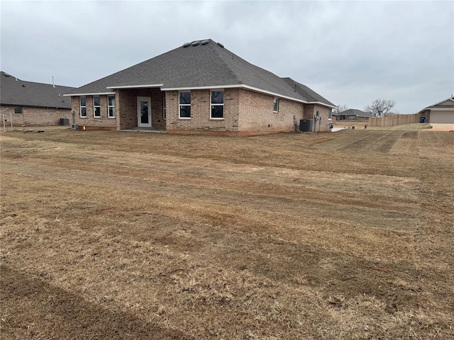 back of property with a lawn and central AC