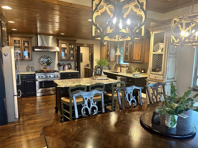 kitchen with sink, wall chimney exhaust hood, a kitchen island, white fridge, and stainless steel stove