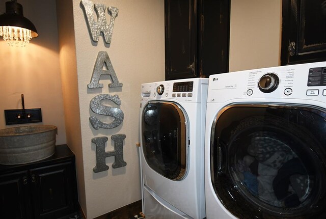 clothes washing area featuring washing machine and clothes dryer and cabinets